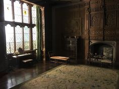 an ornate room with stained glass windows and wood paneling on the walls, along with a large rug in front of a fireplace