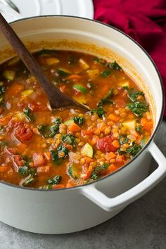 a white pot filled with soup and vegetables