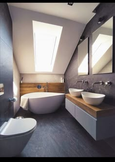 a bathroom with two sinks and a bathtub in the middle of it, under a slanted skylight