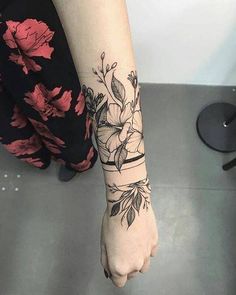 a woman's arm with a flower tattoo on her left wrist and the other hand