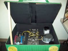 an open suitcase with some wires and other items in it's bottom compartment, sitting on top of a carpeted floor