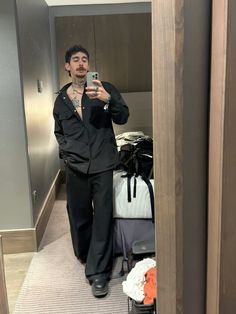 a man taking a selfie in front of a mirror while standing next to luggage