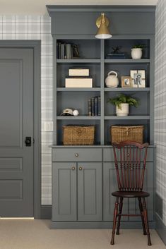 a chair sitting in front of a gray book shelf with baskets on top of it