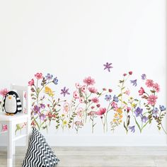 a wall with flowers painted on it and a stuffed animal sitting in front of it