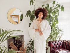 a woman standing in front of a living room with potted plants and a couch