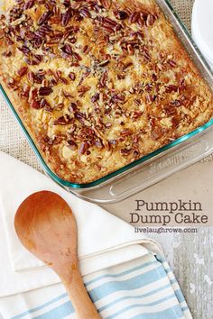 pumpkin dump cake in a glass baking dish with a wooden spoon next to it on a blue and white towel