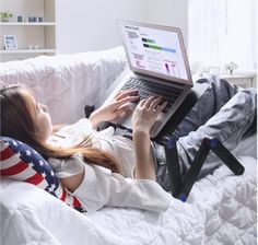 a woman laying on top of a bed using a laptop computer