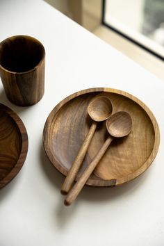 three wooden spoons and two bowls on a white counter top with windows in the background