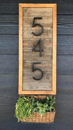 a wooden sign with the number five on it and some succulents in a basket