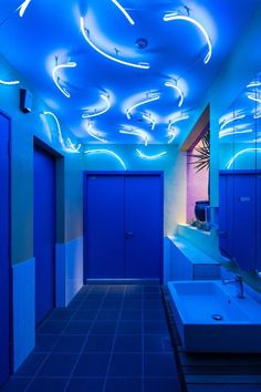 a bathroom with blue walls and lights on the ceiling is shown in this image, it appears to be lit up