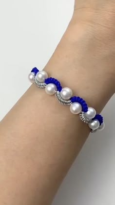 a woman's arm wearing a blue and white beaded bracelet with pearls on it