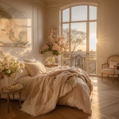 a bedroom with a large window, bed and flowers on the table in front of it