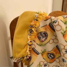 a yellow and white blanket sitting on top of a wooden chair