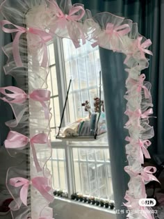 a mirror with pink ribbons hanging from it's sides in front of a window