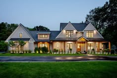 a large white house with lots of windows and lights on it's front porch