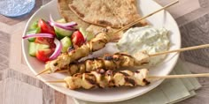 chicken skewers and vegetables on a plate with pita bread