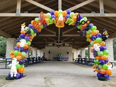 an arch decorated with balloons and decorations for a halloween themed event at the park or school