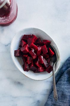 a white bowl filled with beets next to a spoon