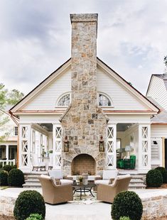 a stone fireplace in the middle of a patio with chairs around it and a table