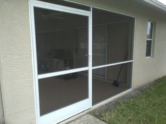 an open sliding glass door on the outside of a house with grass in front of it