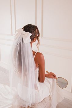 a woman sitting on the floor wearing a veil and holding a mirror in her hand