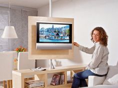 a woman sitting on a white couch in front of a flat screen tv that is mounted to the wall