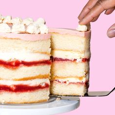 someone cutting into a layered cake with marshmallows and strawberry jam on top