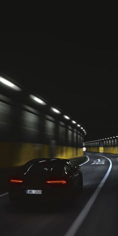 a black sports car driving down a highway at night