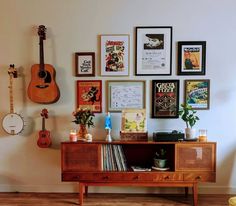 a room with guitars, posters and other items on the wall behind a wooden cabinet