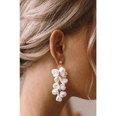 a woman wearing white earrings with flowers on it