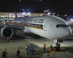 an airplane that is sitting on the tarmac at night with people walking around it