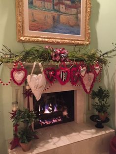 a fireplace decorated for christmas with stockings and garland on it's mantel, surrounded by potted plants