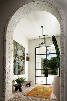 an archway leading into a living room with a cactus in the corner and artwork on the wall