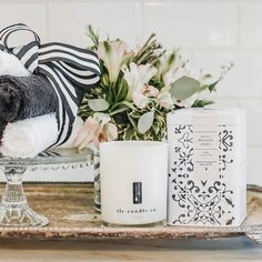 a dog stuffed animal sitting on top of a table next to a candle and some flowers