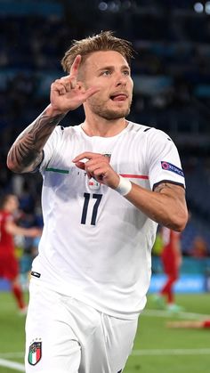 a male soccer player in a white uniform is holding his hand up to the side