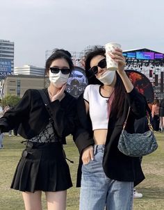 two young women standing next to each other holding coffee cups in front of their faces