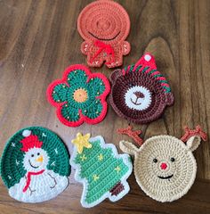 four crocheted christmas ornaments sitting on top of a wooden table