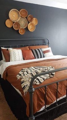 a bed with brown and white pillows on top of it next to a wall mounted wicker baskets