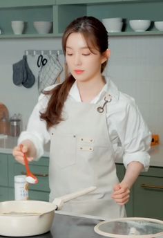 a woman in an apron is holding a spoon