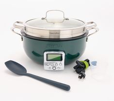 a large green pot with a digital thermometer next to it and two spoons