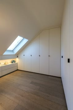 an attic bathroom with skylight and white cabinets on the wall, along with wooden flooring