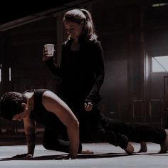 two people doing push ups on the floor with one holding a drink in his hand