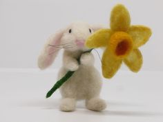 a small stuffed animal holding a flower in it's hand and looking at the camera