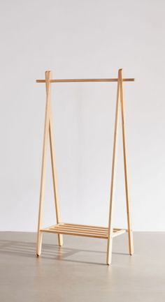 a wooden swing with two bars attached to the top and bottom, in front of a white wall