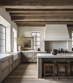 a large kitchen with wooden floors and white walls, has an island in the middle