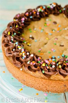 a cookie cake with chocolate frosting and sprinkles on a glass plate