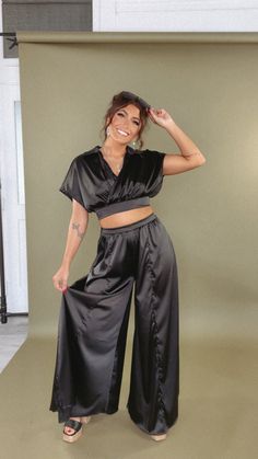 Get ready to turn heads in our Satin Top and Pants Set! This flowy set features a unique wrap effect top and collar neckline. Perfect for adding a little fun to your wardrobe, this top will take you to new heights in style!! Black satin set Top + Pants set Two-piece Wrap effect top Collar neckline Relaxed fit Cropped hem Wide leg Measurements:S: Inseam: 30” | Rise: 13”M: Inseam: 31” | Rise: 14”L: Inseam: 32” | Rise: 15” Model Specs: Emily is wearing a size small in the photo.How will this item f Chic Black V-neck Sets, Chic Two-piece Loungewear Tops, Chic V-neck Matching Set, Black Wide Leg Loungewear Set, V-neck Pant Set For Workwear, Black Short Sleeve Sets For Night Out, Chic Matching Set For Night Out, Style Wide Leg Jeans, Bride Top