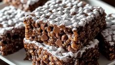 several pieces of chocolate dessert on a white plate with powdered sugar and chocolate chips