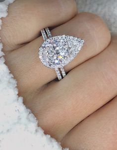 a woman's hand with a diamond ring on top of her finger, in the snow