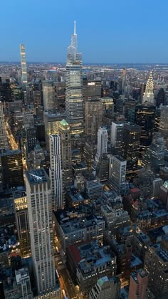 an aerial view of the city at night with skyscrapers lit up and buildings in the foreground